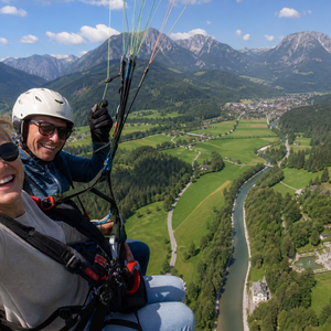 Nina und ihr Pilot beim Tandemflug über Oberammergau – mit Blick auf die Ammergauer Alpen und das Schloss Linderhof