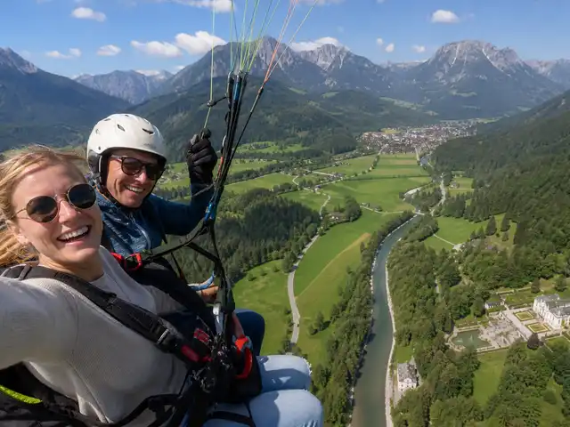 Nina und ihr Pilot beim Tandemflug über Oberammergau – mit Blick auf die Ammergauer Alpen und das Schloss Linderhof